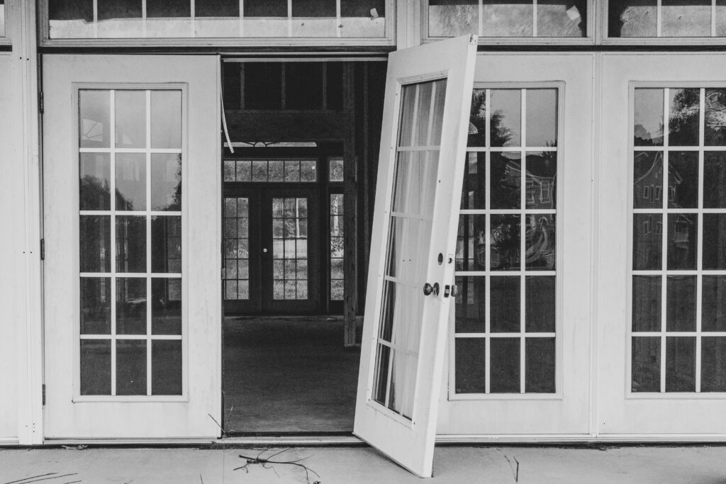 Black and white image of open French doors leading to an empty interior space.
