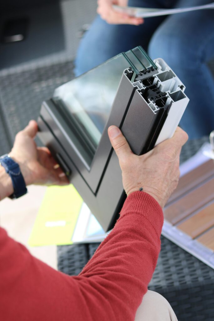 Detail shot of hands examining a window frame section, highlighting construction materials.